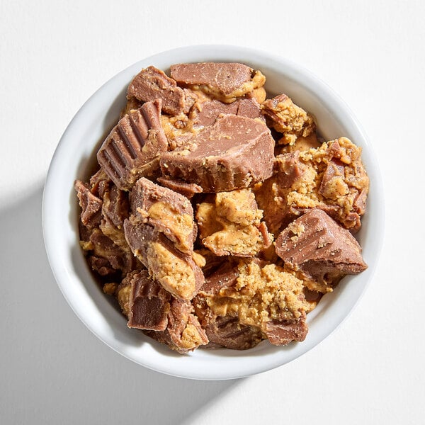 A white bowl filled with chopped pieces of REESE'S peanut butter cups.