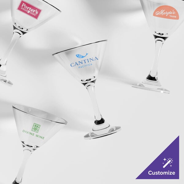 A set of customizable clear cocktail or martini glasses with various printed logos on them.