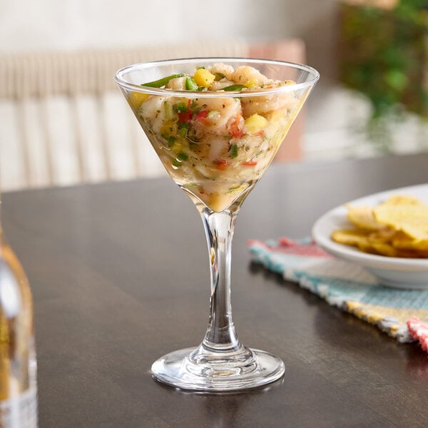 A clear martini glass filled with a shrimp and vegetable cocktail.