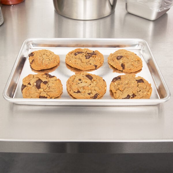 A quarter size aluminum bun or sheet pan holding six chocolate chip cookies.