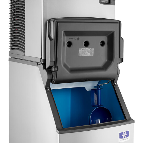 A commercial ice machine with an open storage bin and visible internal components.