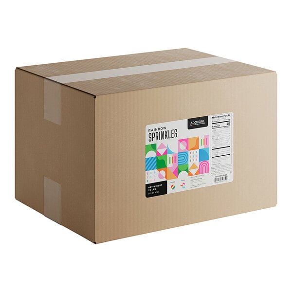 A large cardboard box labeled as containing 25 pounds of Adourne Expressions Rainbow Sprinkles.