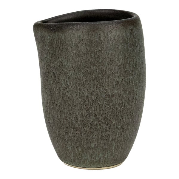 A small green and brown stoneware creamer with a textured surface and an irregular rim.