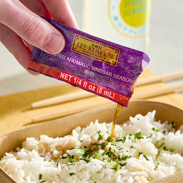 A packet of Lee Kum Kee Selected Aromatic Vinegar Seasoning being poured over a serving of rice.
