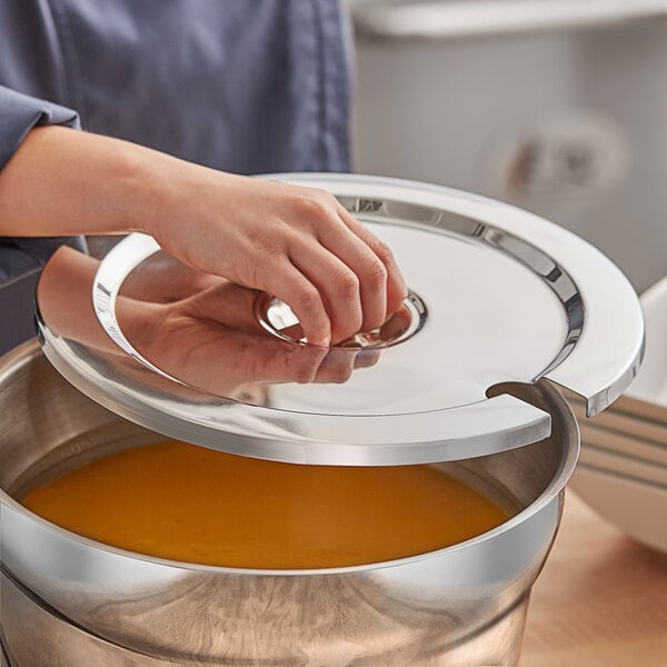 A stainless steel notched vegetable inset cover being placed on a pot.
