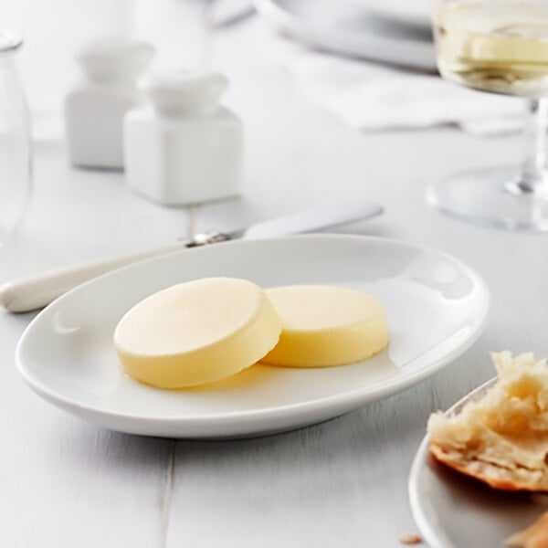 A white plate with two round salted butter medallions.