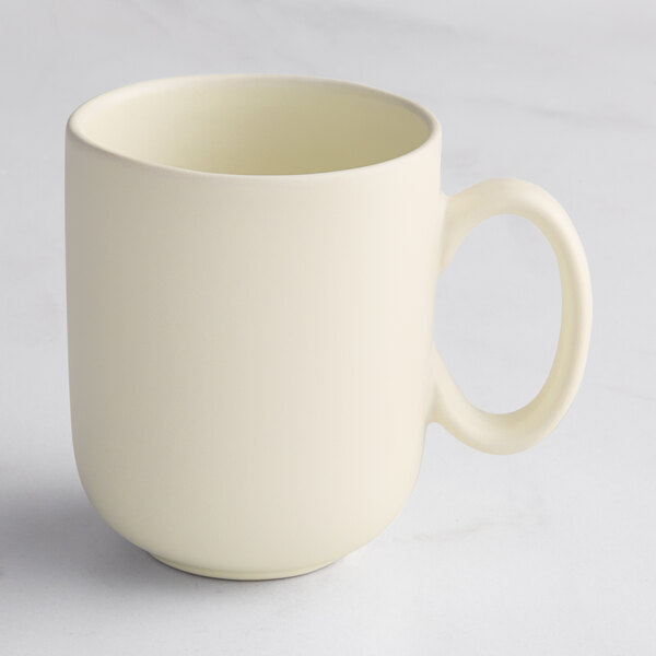 A plain, matte-finish, off-white mug with a rounded handle, shown on a light surface.