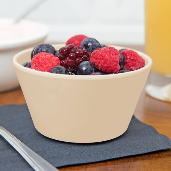 A close-up of a tan SuperMel bowl filled with fruit.