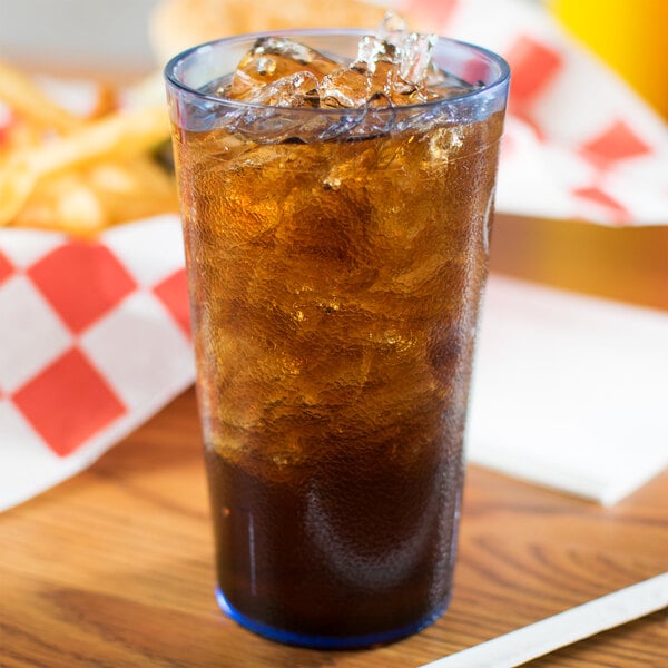 A Carlisle blue plastic tumbler filled with brown liquid and ice on a table.