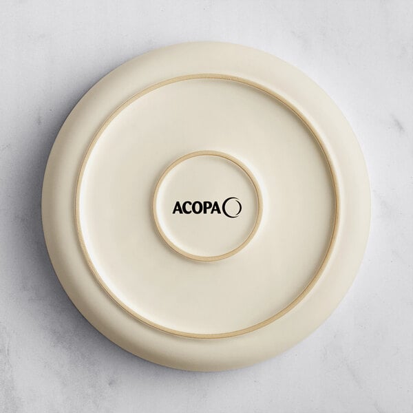 A round, cream-colored plate or bowl with a matte finish and the word 'ACOPA' printed on the bottom center.