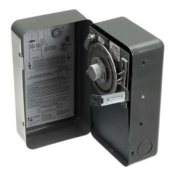 A mechanical time clock timer in a metal enclosure with an exposed dial and internal wiring diagram.