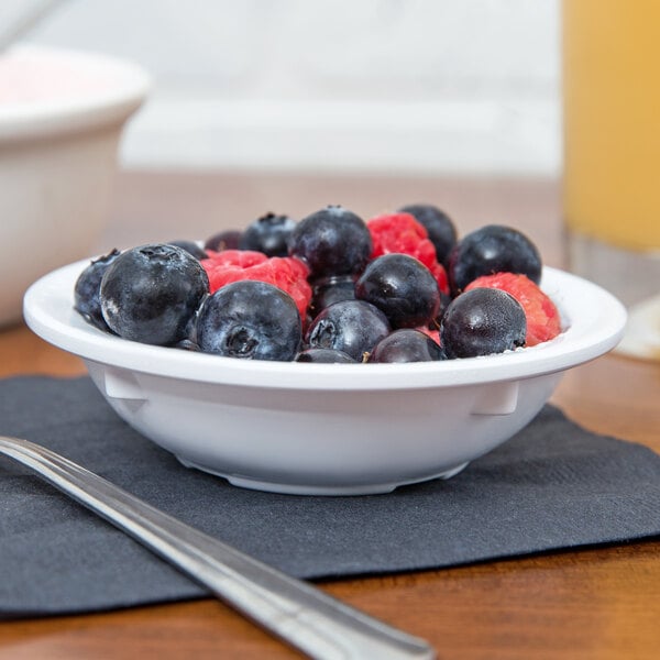 A white GET supermel bowl filled with blueberries and raspberries.