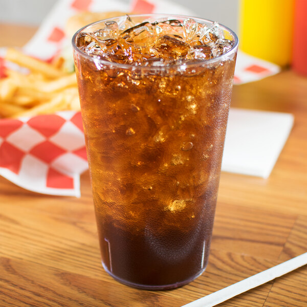 A Carlisle clear plastic tumbler filled with brown liquid and ice with a straw.