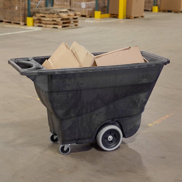 A black Rubbermaid tilt truck with cardboard boxes in it.