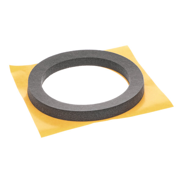 A round foam gasket for an exhaust blower, shown on a square piece of yellow backing paper.