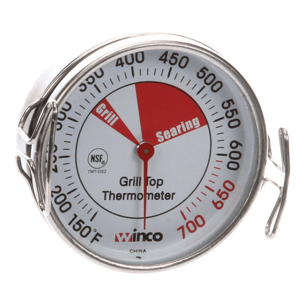 A round grill top thermometer with a metal casing and a temperature dial labeled for grilling and searing zones.