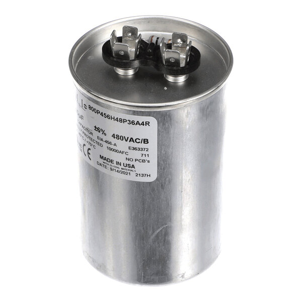A cylindrical metal run capacitor with two electrical terminals on top and a product label on the side.