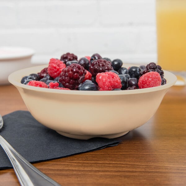 A tan SuperMel bowl filled with berries on a table.