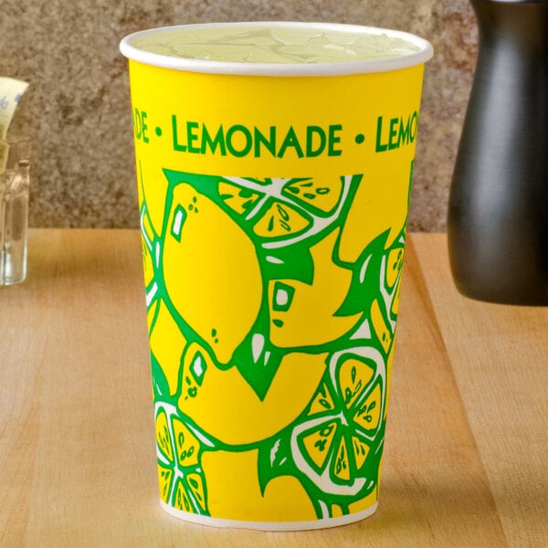 A yellow paper lemonade cup with a green design on a counter.