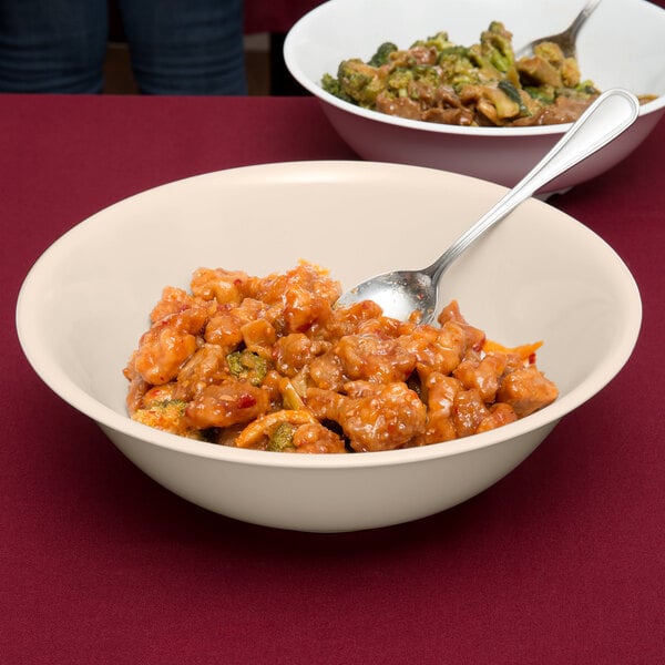 A tan SuperMel melamine bowl filled with food with a spoon in it.