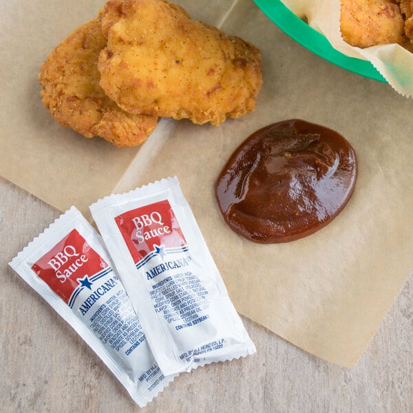 A table with chicken nuggets and BBQ sauce packets.