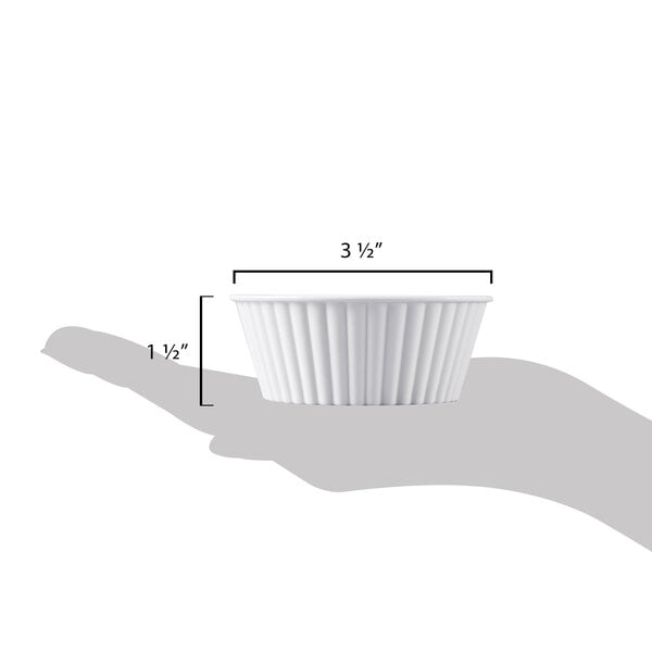 A hand holding a white fluted Carlisle ramekin with measurements.
