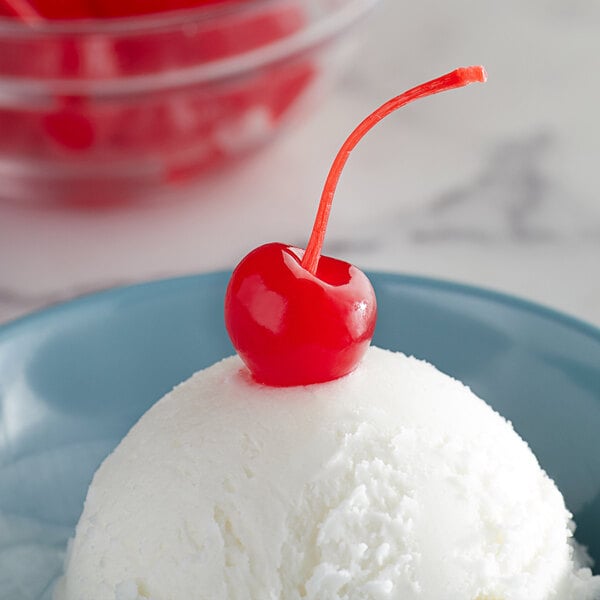 A maraschino cherry with a stem placed on top of a scoop of vanilla ice cream.