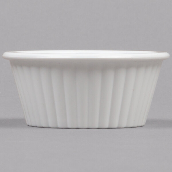 A close up of a white Carlisle fluted plastic ramekin.