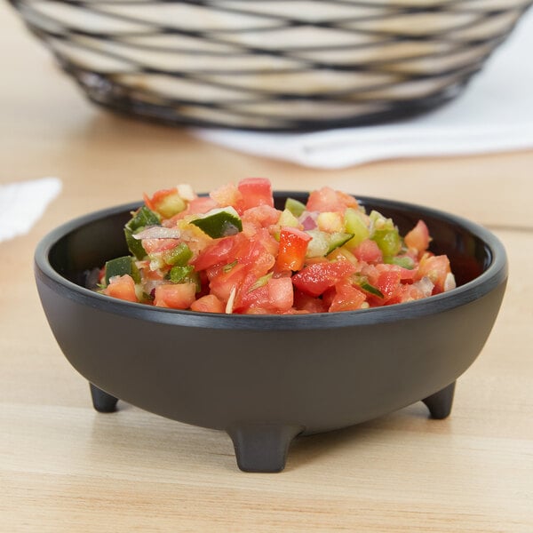 A Carlisle melamine molcajete ramekin filled with salsa on a table.