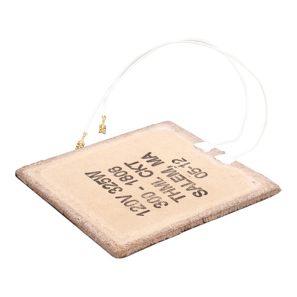 A flat, rectangular foil heating element with attached wires and printed specifications on its surface.