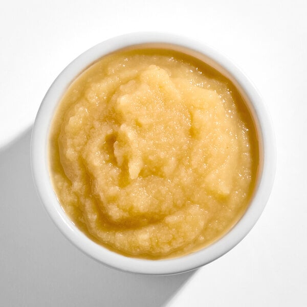 A bowl filled with a light yellow, smooth and chunky applesauce.