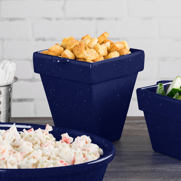 A Tablecraft blue speckled cast aluminum square condiment bowl with food in it on a counter.