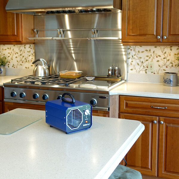 An OdorStop OS1200 ozone generator air purifier with a blue casing and control knob, placed on a kitchen countertop.