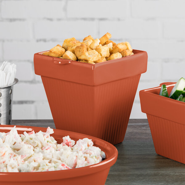 A table with three Tablecraft copper condiment bowls of food on a table in a salad bar.