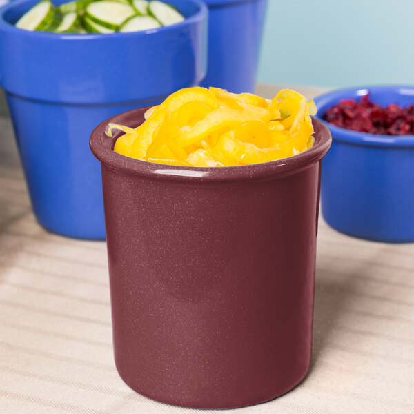 A maroon speckled Tablecraft condiment bowl with yellow food inside on a counter.