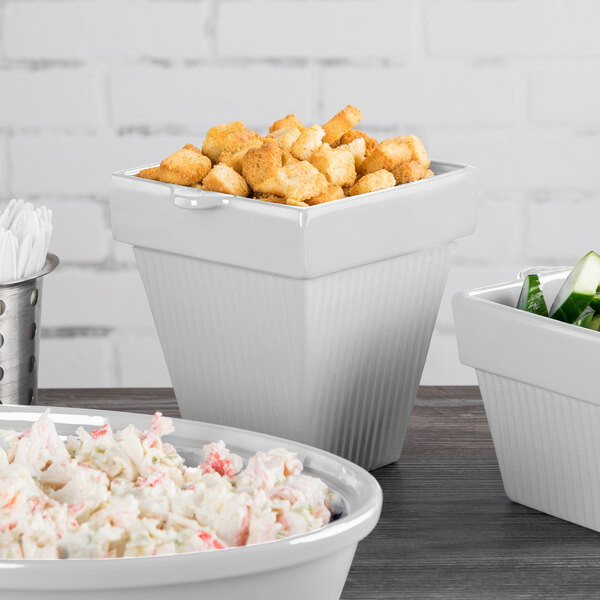 A Tablecraft natural cast aluminum square condiment bowl filled with green vegetables on a salad bar counter.