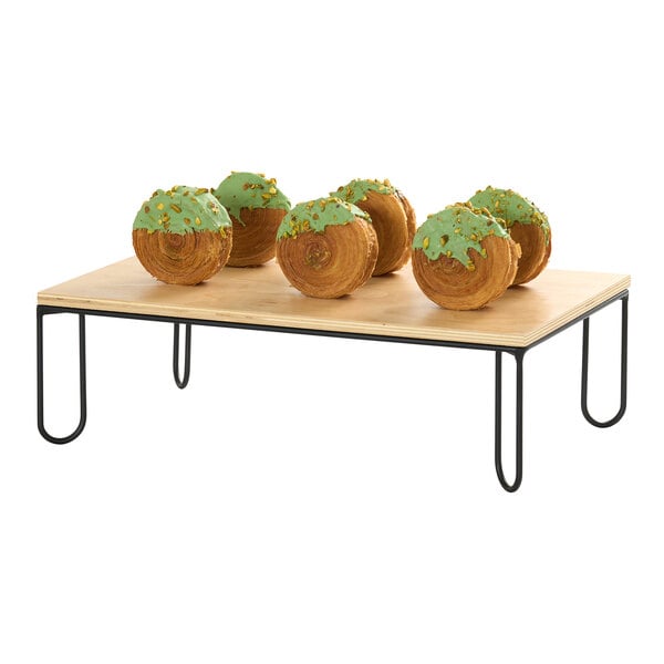 A rectangular wooden display riser with a black wire frame, shown holding pastries.