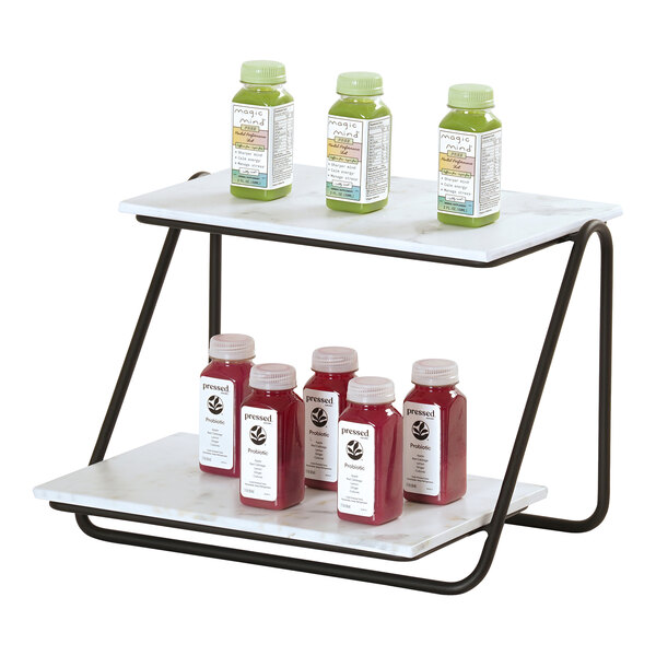 A two-tiered angled display shelf with a black metal frame and white shelves, holding several bottles of juice.