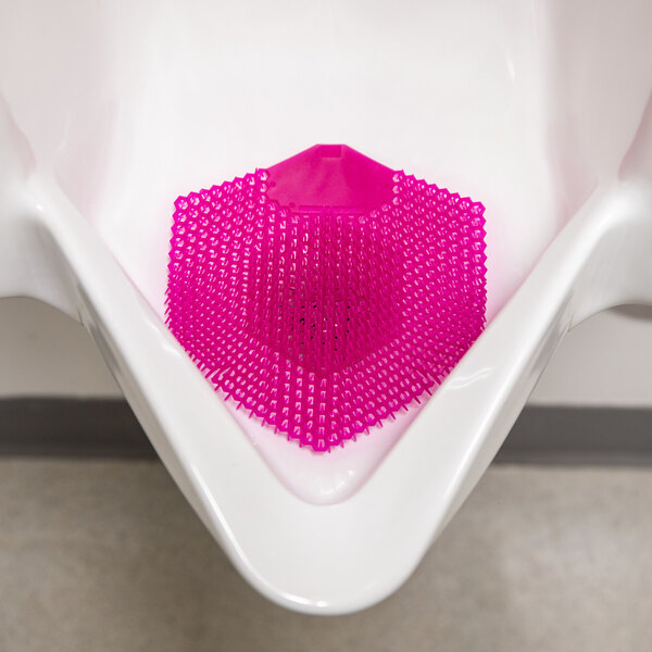A pink EVA gel urinal screen placed inside a white urinal.