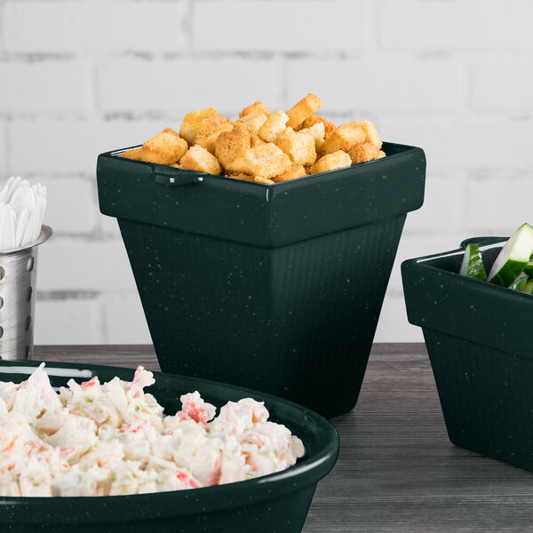 A Tablecraft hunter green and white speckled cast aluminum square condiment bowl filled with food on a table.