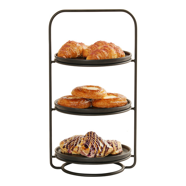 A three-tier metal plate stand holding assorted pastries on each level.