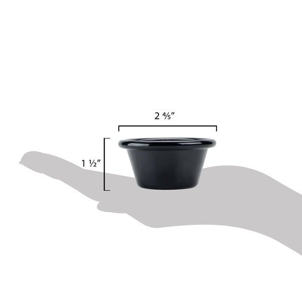 A hand holding a black Carlisle smooth plastic ramekin with measurements.