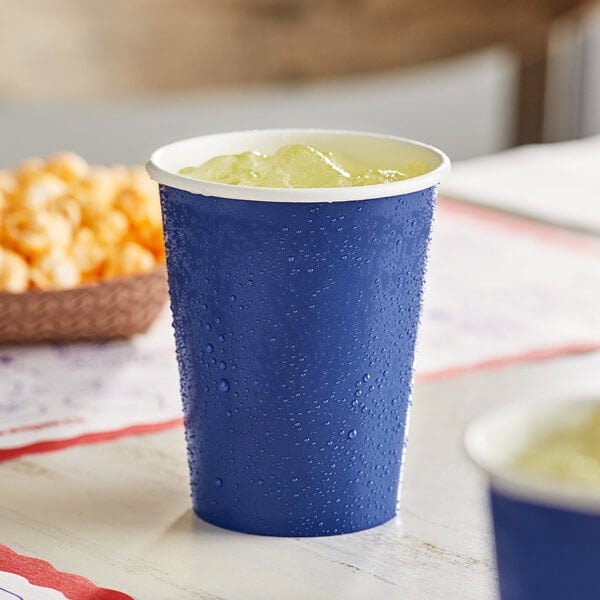 A navy blue Creative Converting paper cup filled with ice on a table.