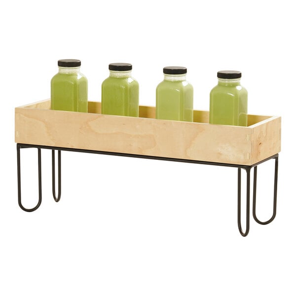 A rectangular wooden box with a black wire riser frame, shown holding four green bottles with black caps.