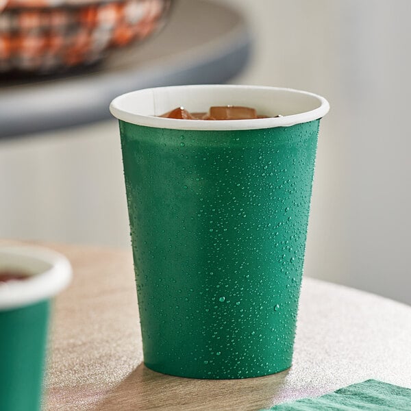 A close up of a Creative Converting Hunter Green paper cup with water droplets on it.