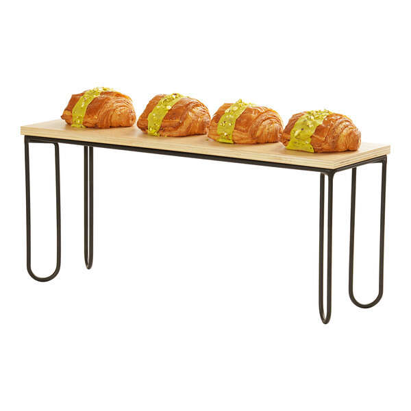 A rectangular black wire riser frame with a wooden top, used for displaying food items.