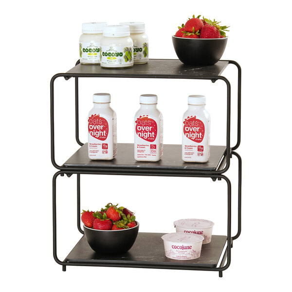 A three-tiered black metal modular frame shelf displaying jars, bottles, bowls of strawberries, and yogurt cups.