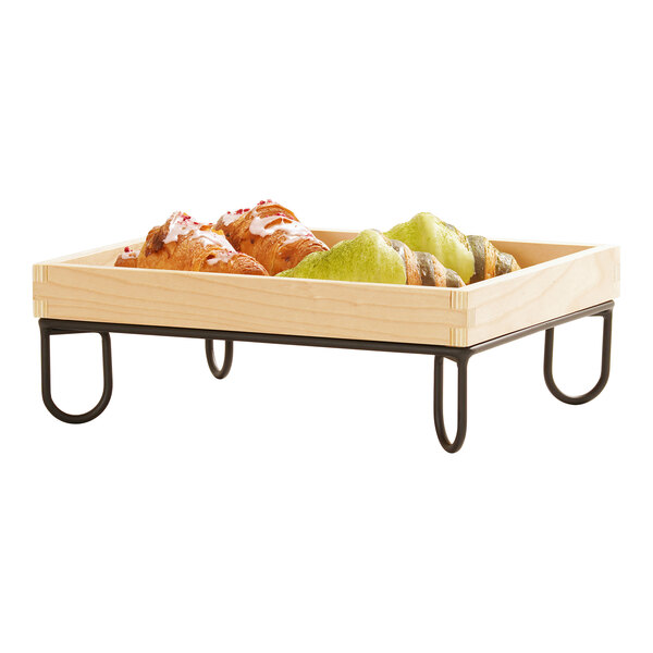 A rectangular wooden tray with a black wire riser frame, holding assorted pastries.