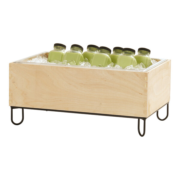 A wooden ice housing container with a metal stand, holding several green bottled drinks on ice.