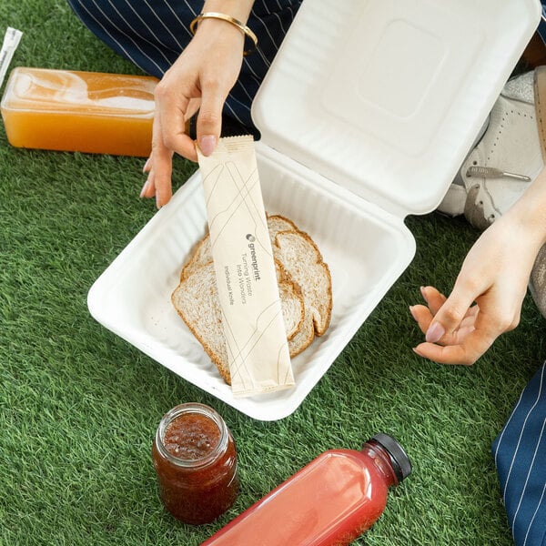 A white compostable sugarcane fiber clamshell take-out container holding slices of bread.